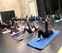 Auf der Bühne in der Nendinger Donau-Hallen liegen auf Yogamatten auf dem Rücken die Teilnehmer des Kurses und strecken jeweils ein Bein in die Luft.