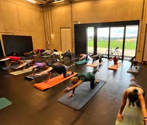 Auf der Bühne in der Nendinger Donau-Hallen knieen die Teilnehmer des Kurses auf ihren Yoga-Matten und strecken jeweils ein Bein nach hinten und ein Arm nach vorne aus.